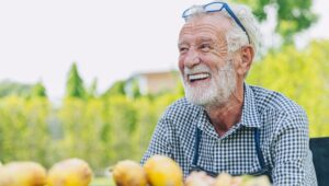 Older man smiling in garden with lemons